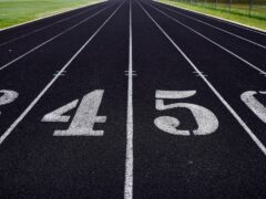 A view of a numbered running track with grassy fields in the background