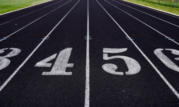 A view of a numbered running track with grassy fields in the background