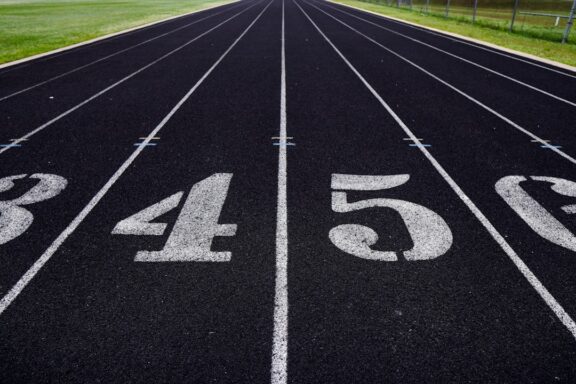 A view of a numbered running track with grassy fields in the background