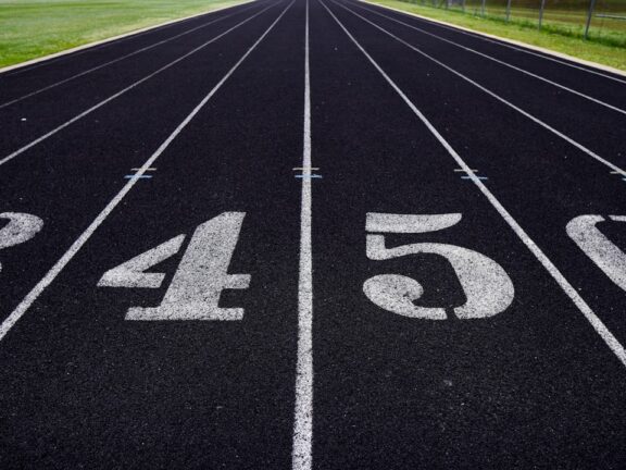 A view of a numbered running track with grassy fields in the background